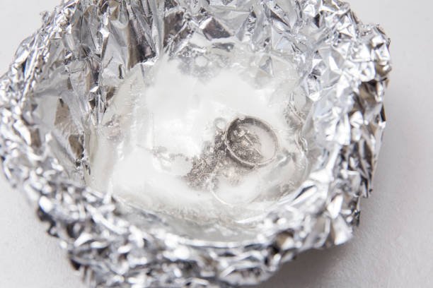 A solution of baking soda(Sodium bicarbonate) and warm water will remove the tarnish from silver when the silver is in contact with a piece of aluminium tin foil. Pouring hot water over silver.